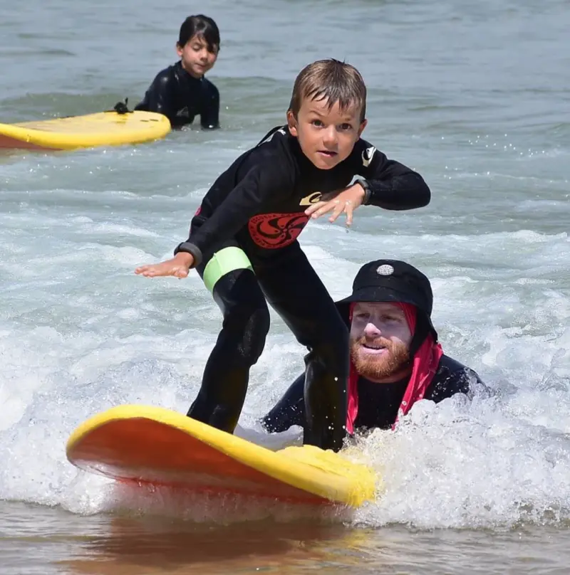 niño pequeño sobre en clase de surf tabla de surf en el mar