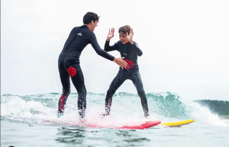 niño y joven en el mar haciendo surf