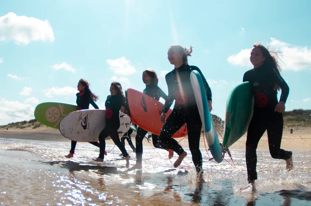 niñas corriendo al mar con sus tablas en las colonias de la Escuela Cántabra de Surf