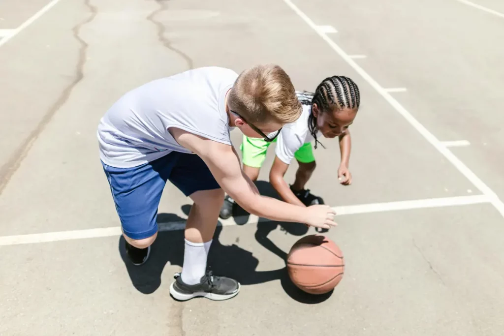 Dos niños jugando al baloncesto. Beneficios del deporte en los niños.