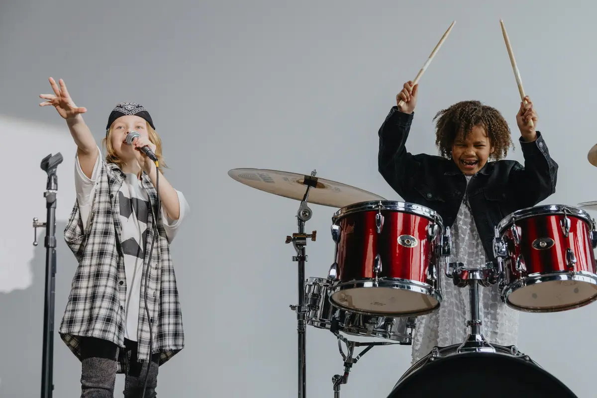 Dos niños cantando y tocando la bateria