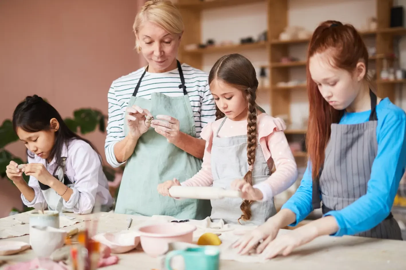 Beneficios de las actividades extraescolares. Niñas en clase de cerámica y arcilla con profesora.